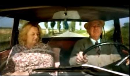 Det eldre ekteparet morer seg på bilturen – men sjekk ansiktsuttrykket på sjåføren de passerer.