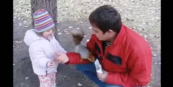 Far og datter mater ekorn i parken, og får seg en god latter når den gjemmer nøttene!