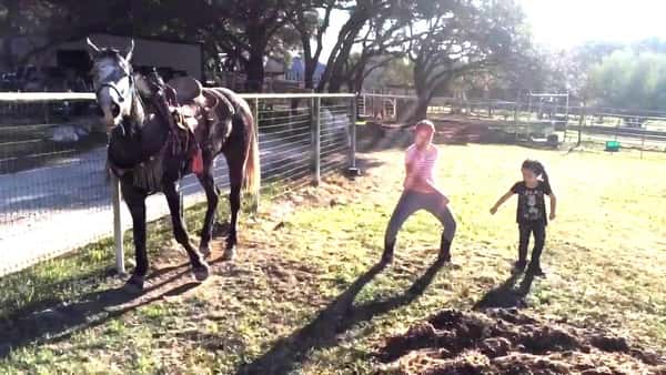 Jentene setter på musikken og danser på jordet, men legg merke til hesten!